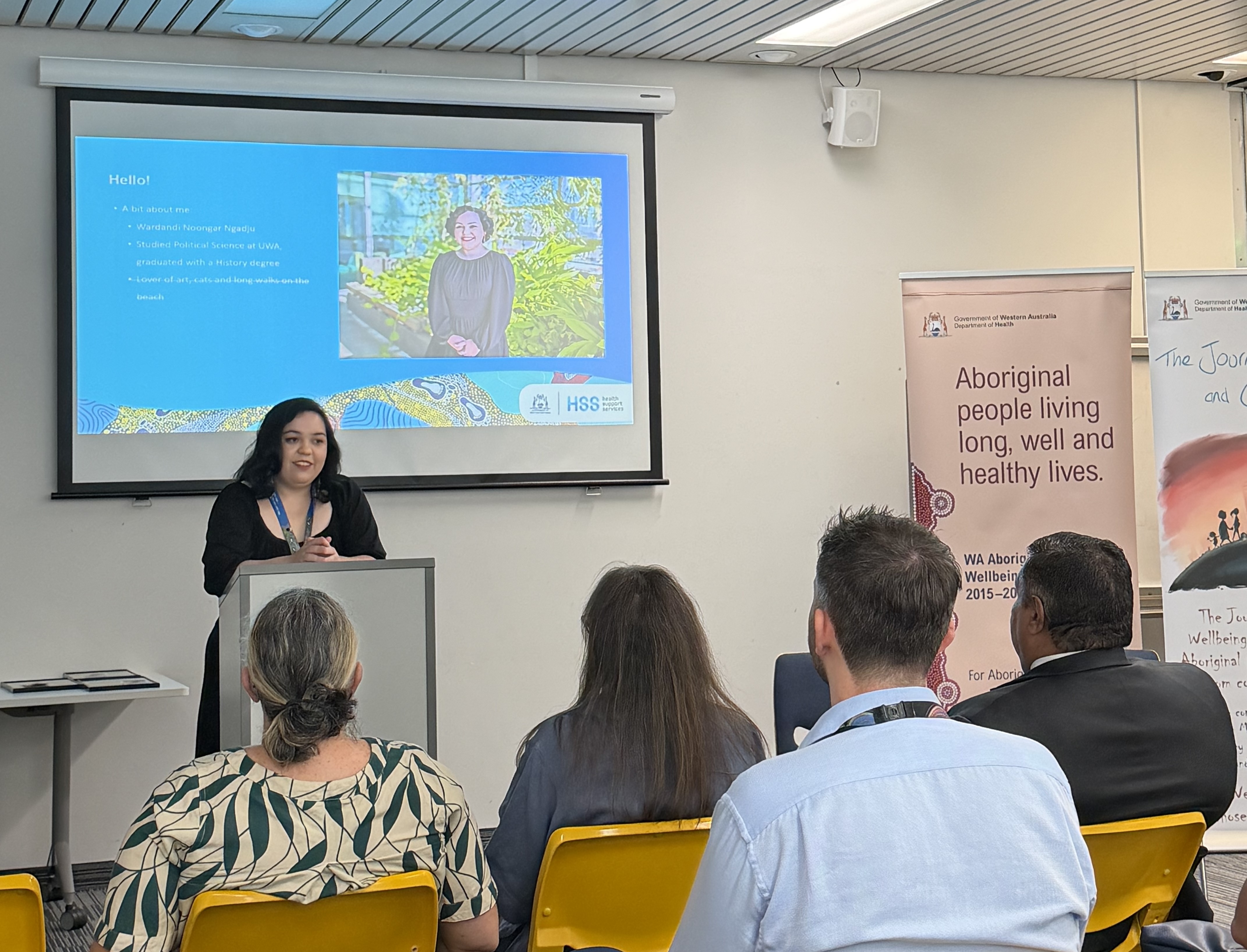 Person standing at a lectern speaking to a group of people