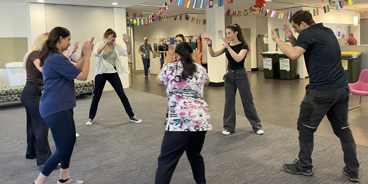 People standing in a circle actioning a self-defence move