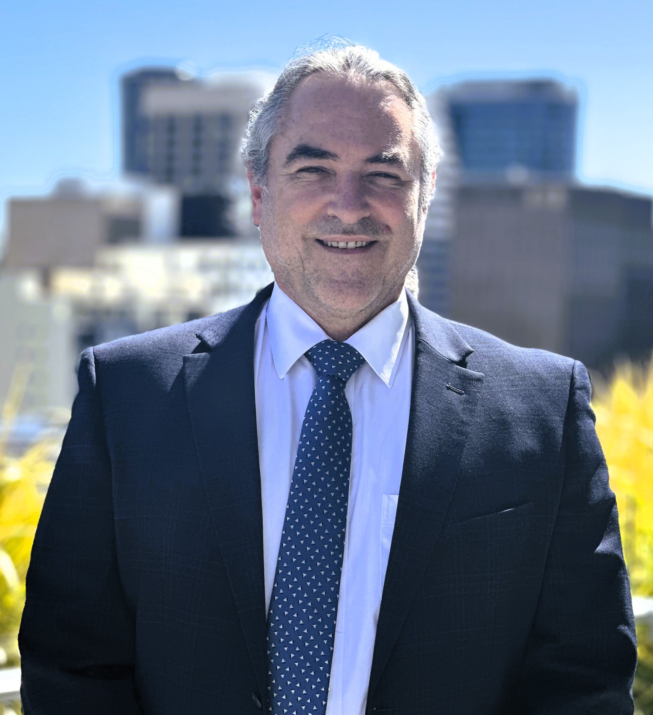 Man wearing a blue suit with striped tie smiling at the camera