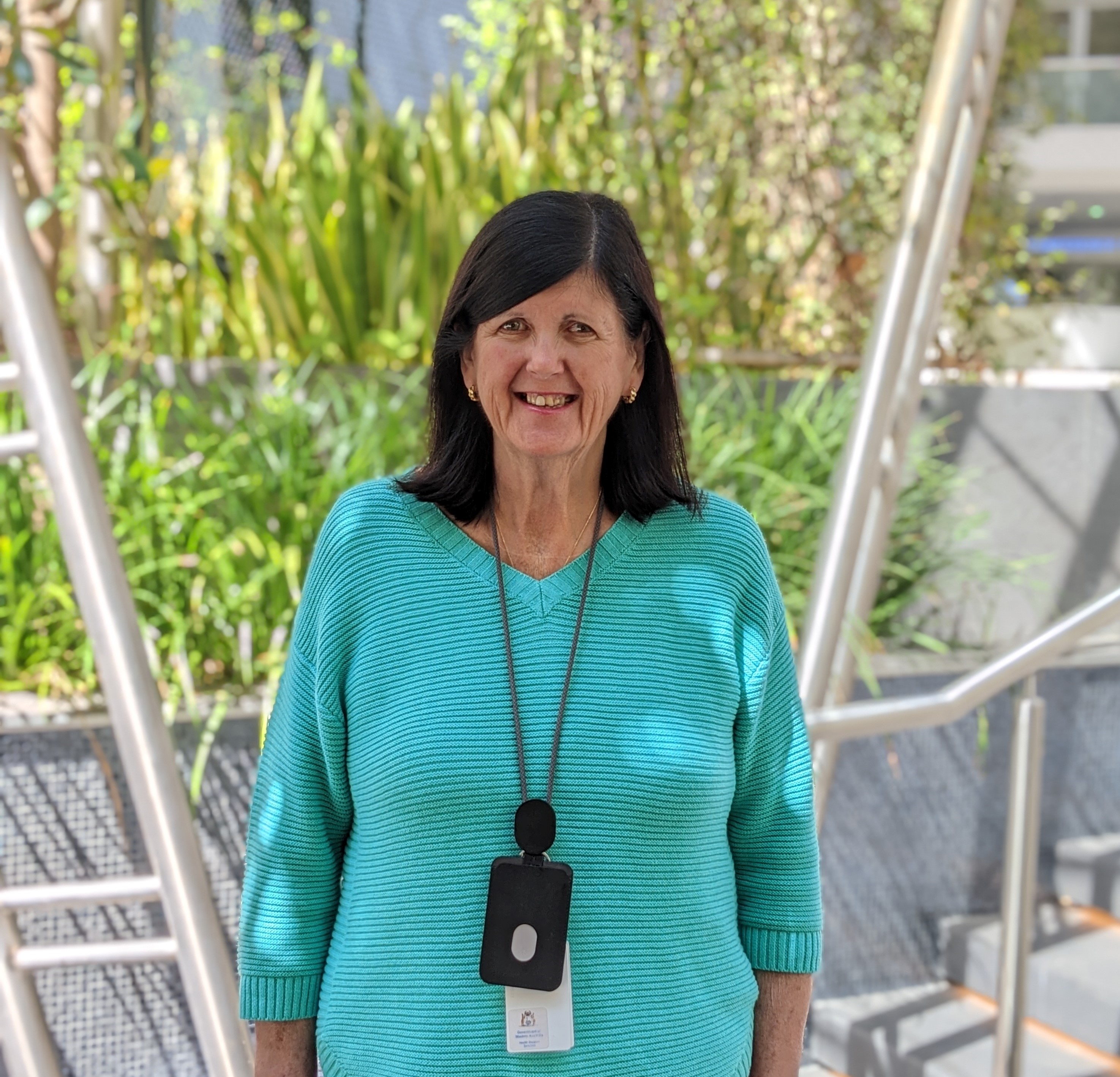 Woman wearing an aqua coloured jumper smiling for a photo