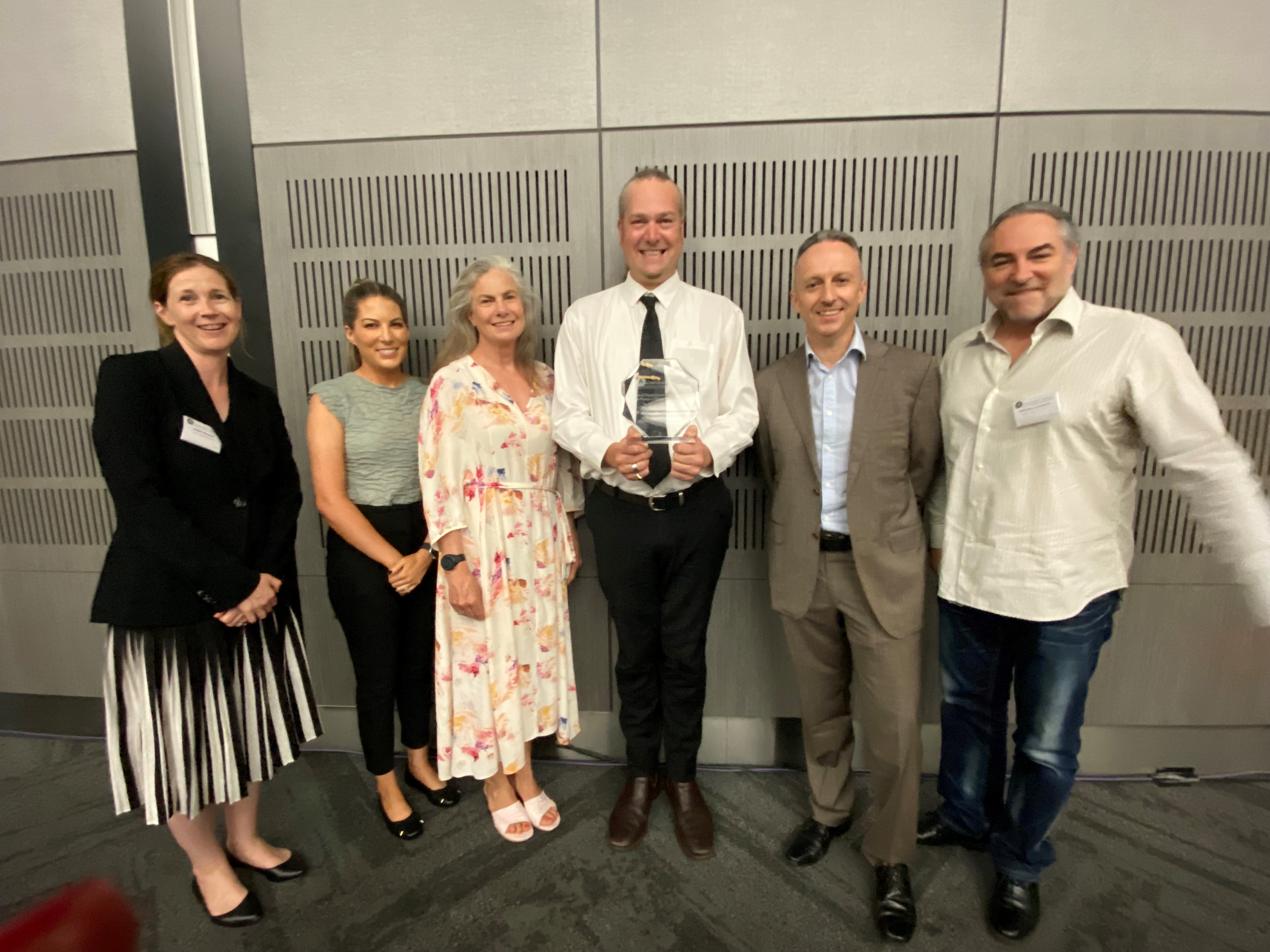 Group of people standing together with one holding an award