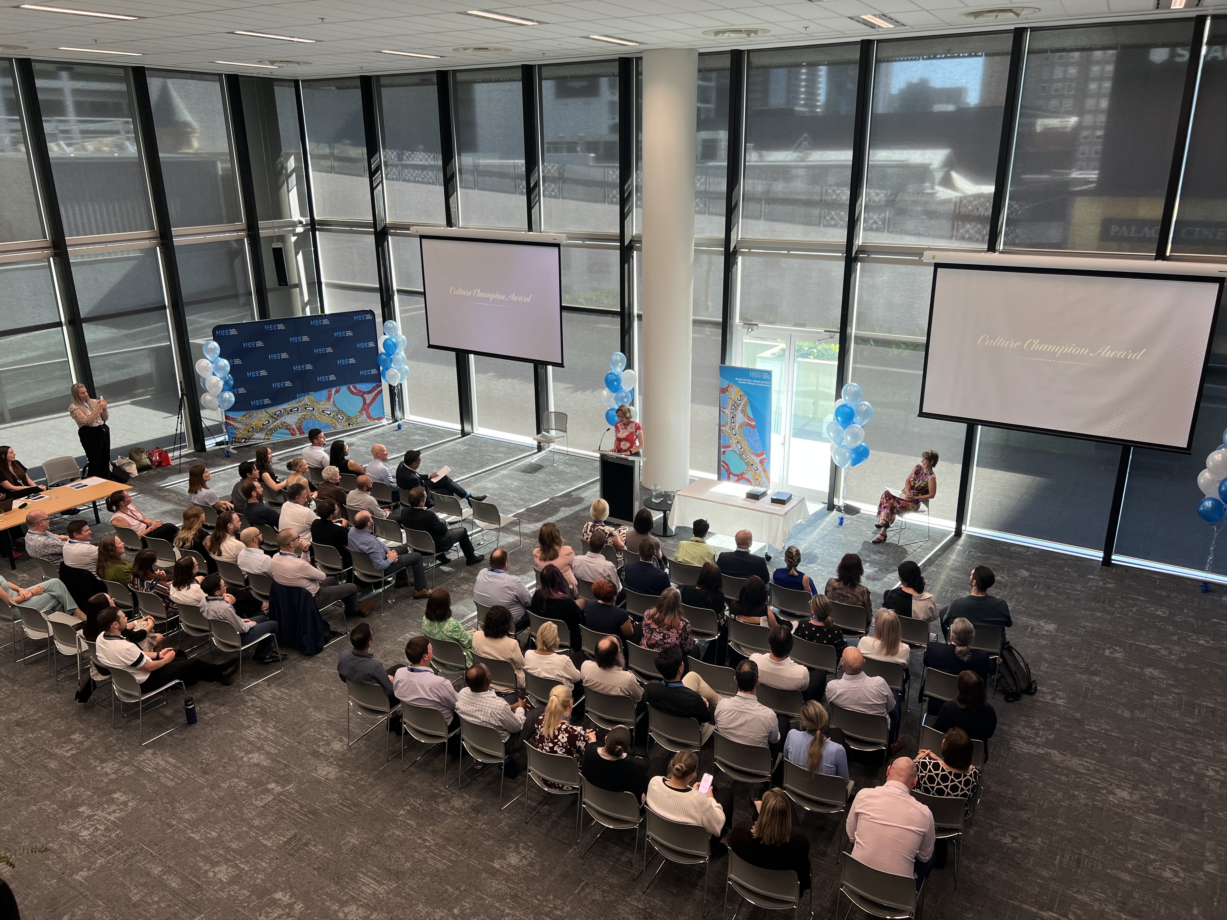 A group of people seated in rows listening to a presenter 