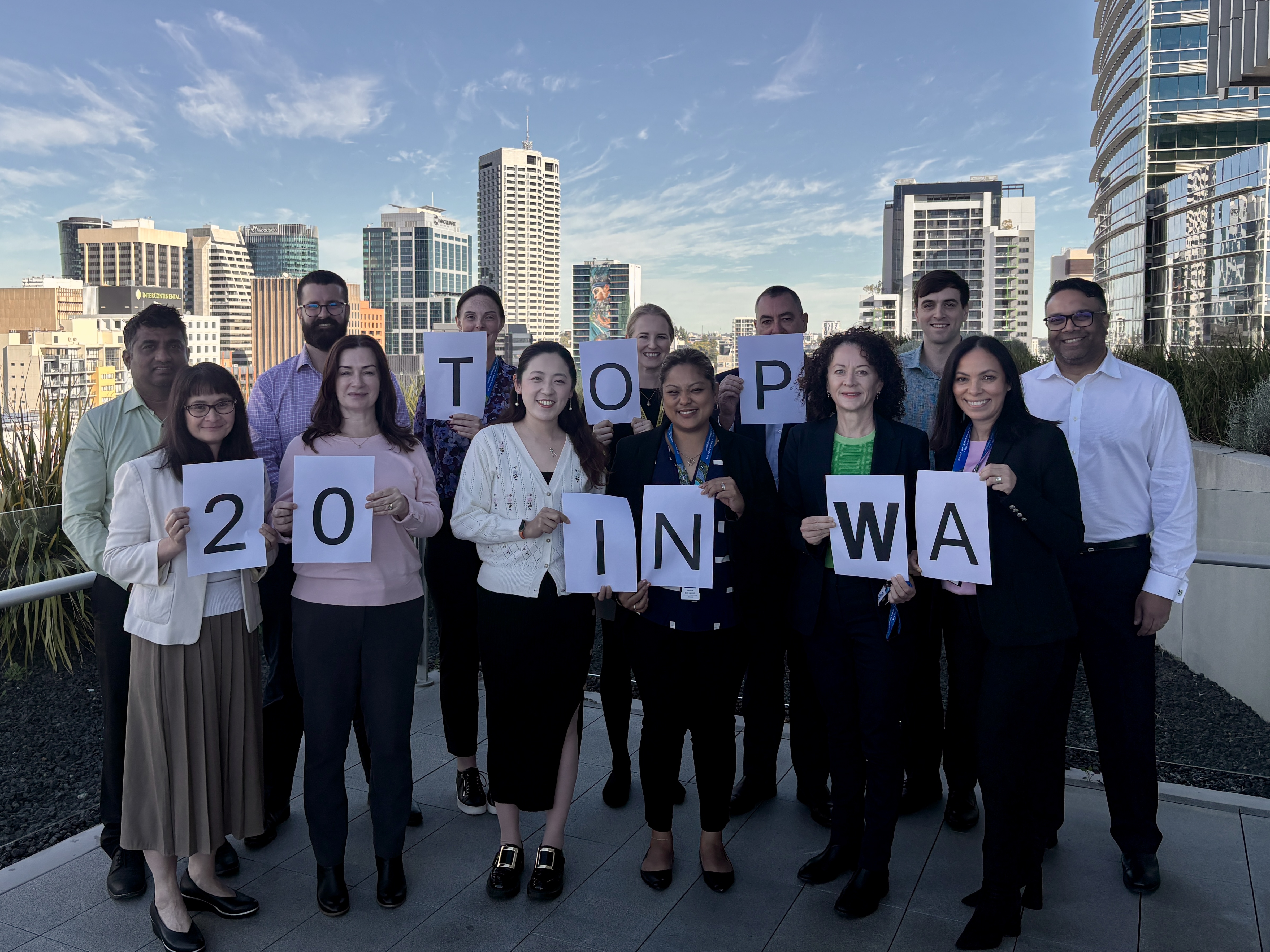 A group of people standing together hold a paper that spells out Top 20 in WA