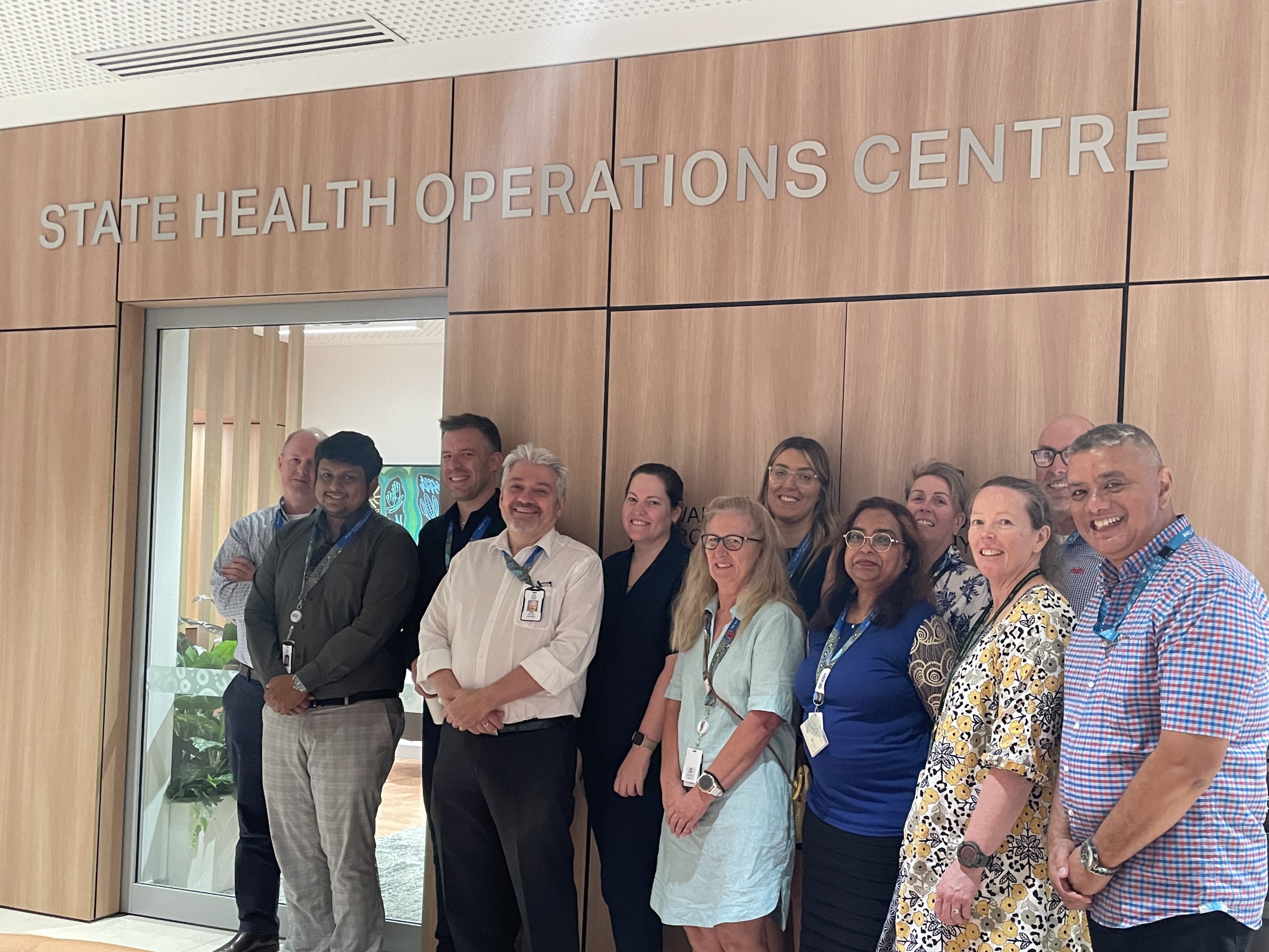 A group of people smiling under a State Health Operations Centre sign