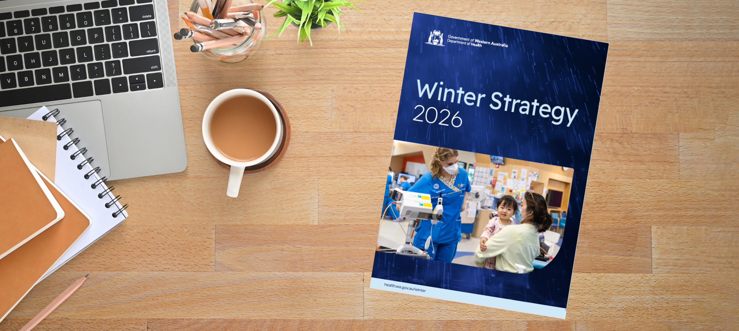 A desk with the Winter Strategy 2026 document, coffee, laptop and notebook