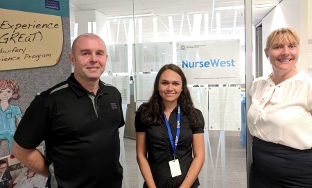Two NurseWest staff members standing with Aboriginal cadet student in front of NurseWest poster