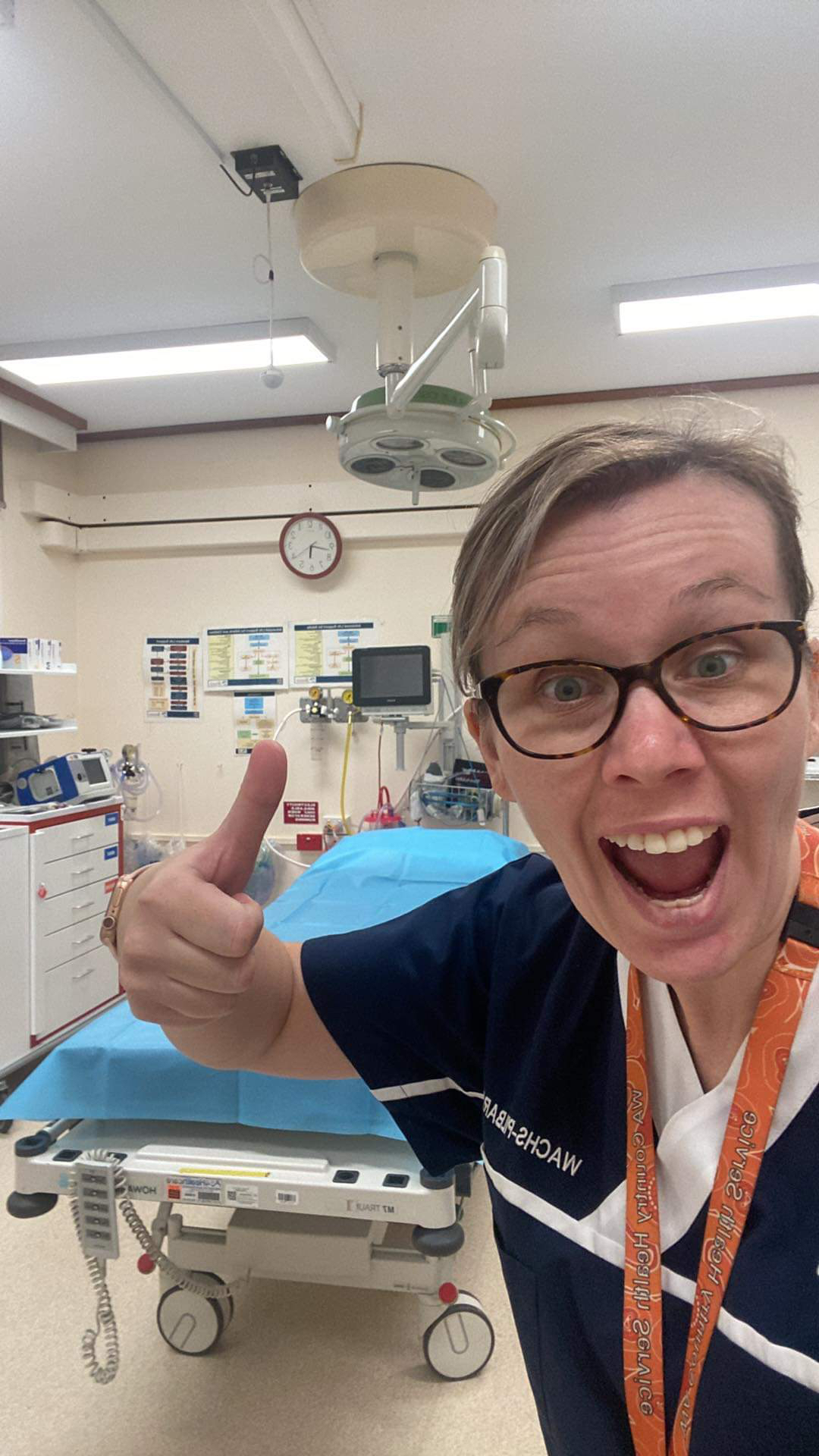 woman holding her thumb up with a big smile on her in an ED room