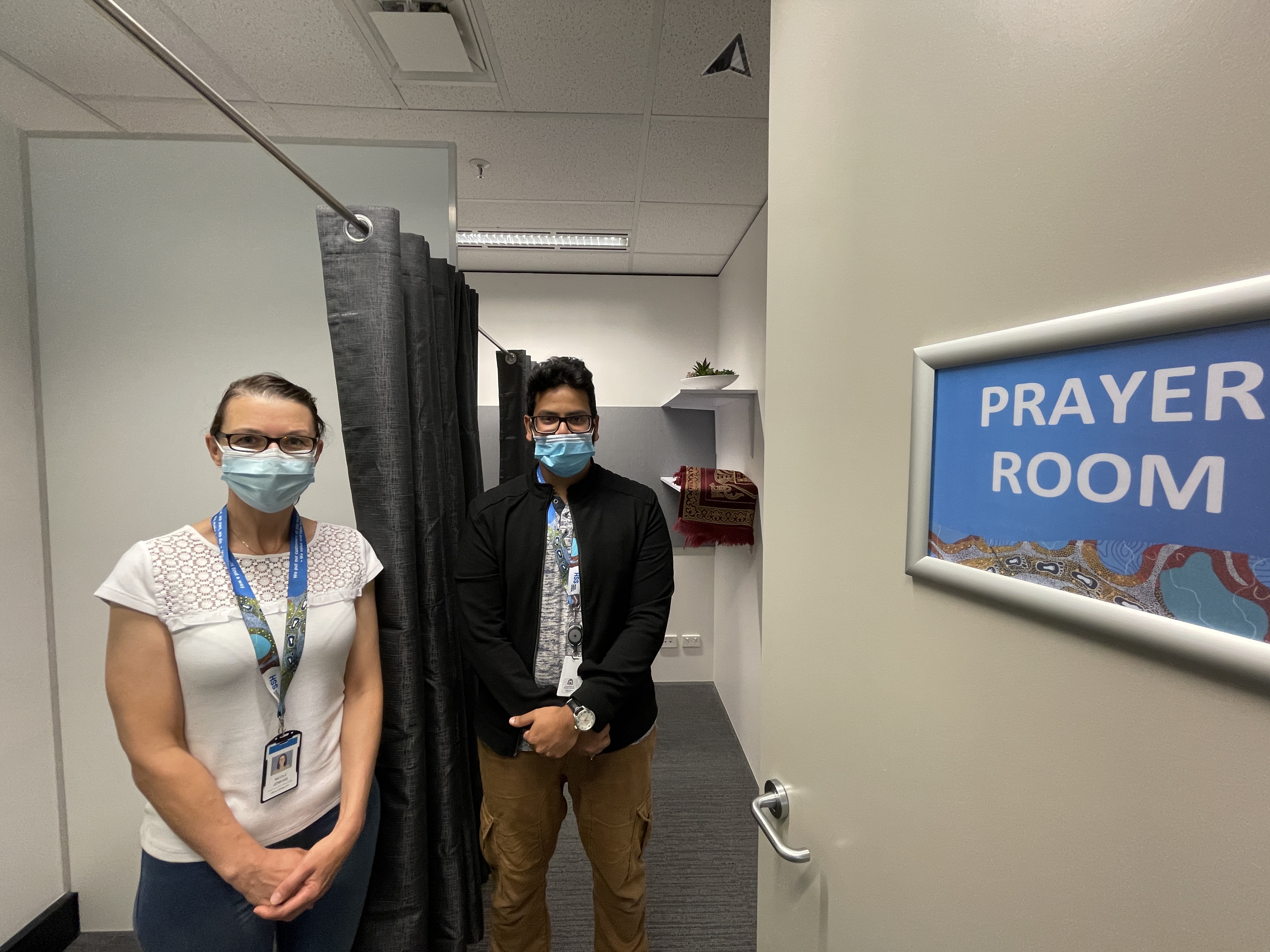 two people with face masks standing in HSS' prayer room.